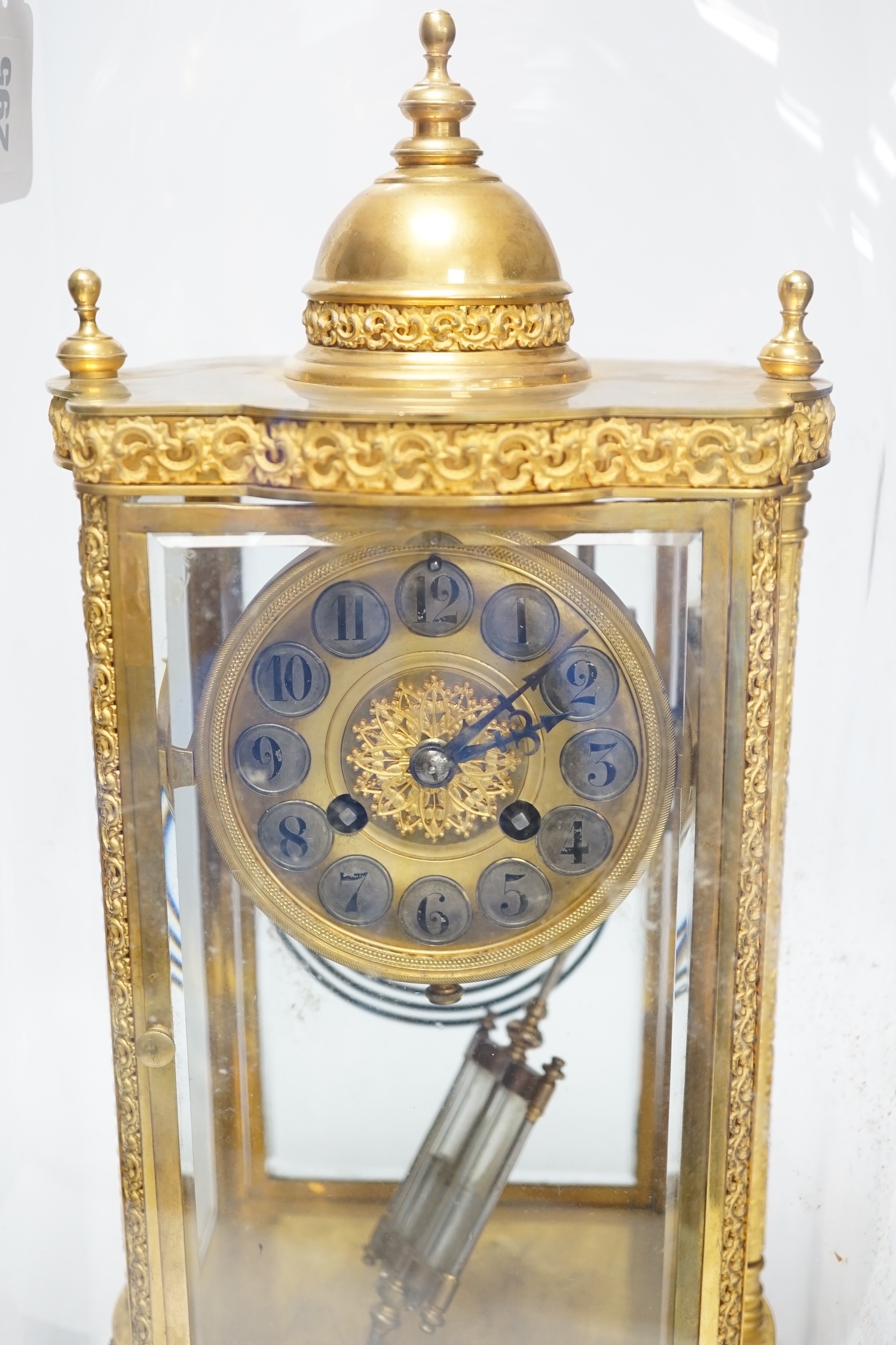 A French four glass mantel clock striking on a coiled gong with gilt brass frame and mercury pendulum, on a stand under a glass dome, 55cm high, with brass presentation label to stand dated December 1903